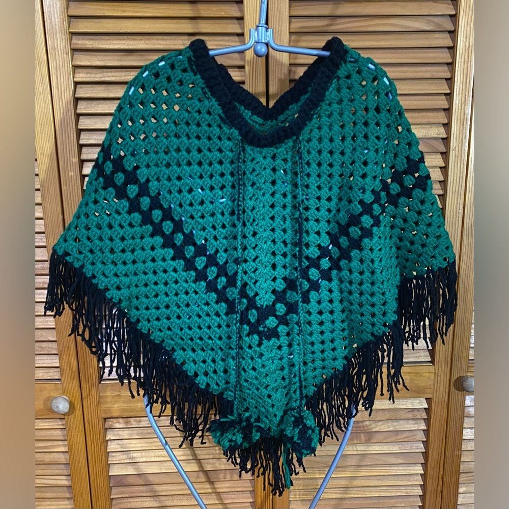 Knit poncho with poof balls and fringe